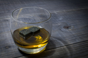 Glass of Whisky with rocks on a rustic wooden table