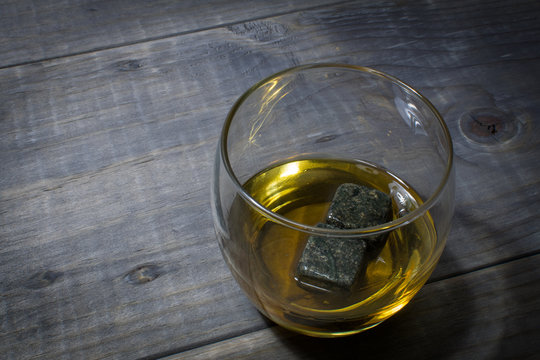 Glass of Whisky with rocks on a rustic wooden table