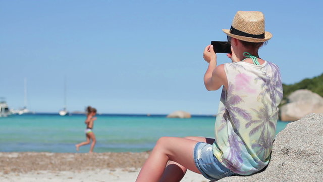 Young woman uses a smartphone to video a beautiful view at the beach