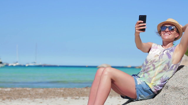 Happy girl on vacations taking self photo on sea background at the beach