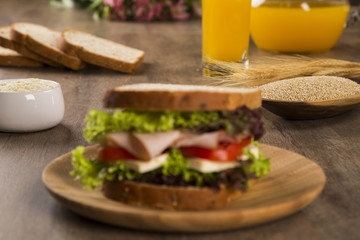 Sandwich on a white plate with turkey breast, tomato and lettuce.