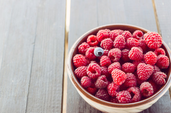 Fresh raspberries in plate on a wooden table