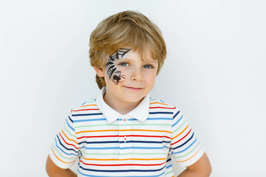 little kid boy with face painted with a spider web