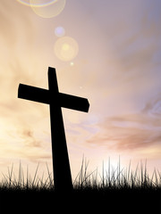 Black cross in grass ar sunset