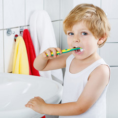 Lovely toddler boy brushing his teeth, indoors
