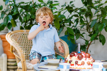 Little boy celebrating his birthday in home's garden with big ca