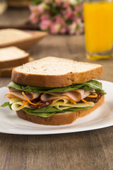 Sandwich on a white plate with turkey breast, tomato and lettuce