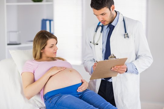 Doctor giving advice to lying pregnant patient