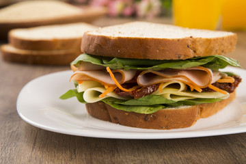 Sandwich on a white plate with turkey breast, tomato and lettuce