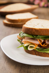 Sandwich on a white plate with turkey breast, tomato and lettuce