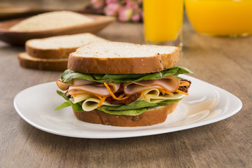 Sandwich on a white plate with turkey breast, tomato and lettuce