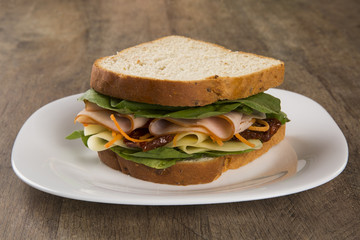 Sandwich on a white plate with turkey breast, tomato and lettuce