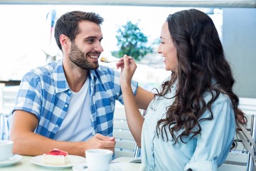 Young happy couple feeding each other with cake 