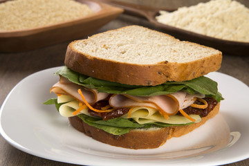 Sandwich on a white plate with turkey breast, tomato and lettuce