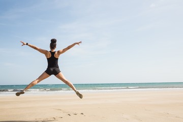 Fototapeta na wymiar Fit woman leaping on the sand