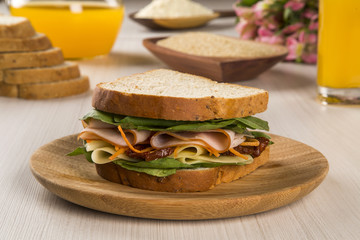 Sandwich on a white plate with turkey breast, tomato and lettuce