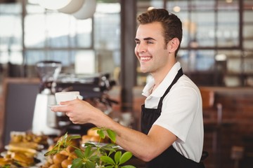 Smiling barista offering cup of coffee