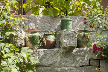 Fototapeta na wymiar Old colorful clay pots placed in niche of granite block stone garden wall