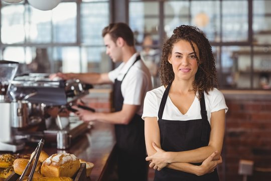 Smiling waitress with arms crossed in front of colleague