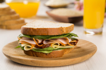 Sandwich on a white plate with turkey breast, tomato and lettuce