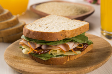 Sandwich on a white plate with turkey breast, tomato and lettuce