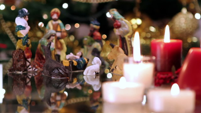 Christmas nativity scene with candles in front of Christmas tree. 