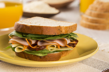 Sandwich on a white plate with turkey breast, tomato and lettuce
