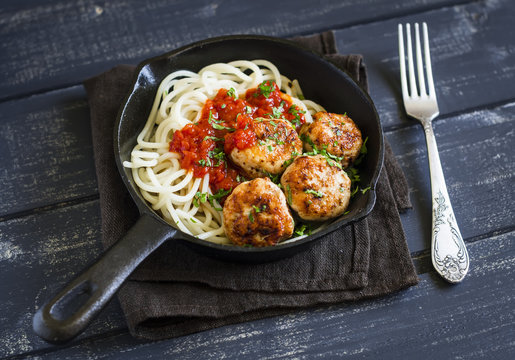 chicken meatballs and spaghetti in a pan on a  dark wooden background