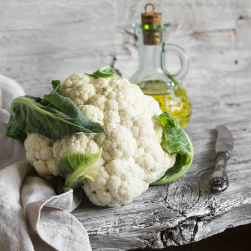 fresh cauliflower and olive oil on a light wooden surface