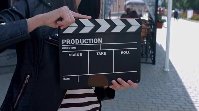 Beautiful girl with a clapperboard on the streets