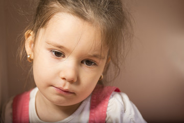 Expressive little girl, melancholic, thinking away, studio shot on brown background