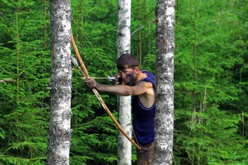 Naklejka na ściany i meble Молодой человек в лесу с луком и стрелами