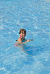 Fototapeta na wymiar Smiling girl in the pool with blue water