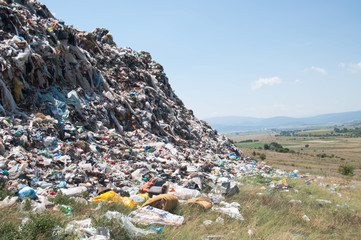 Landfill near crop fields. Enormous Trash wave near fields