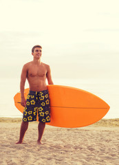 smiling young man with surfboard on beach