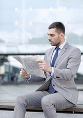 young serious businessman newspaper outdoors