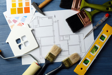 Construction instruments, plan, color samples and brushes on wooden table background