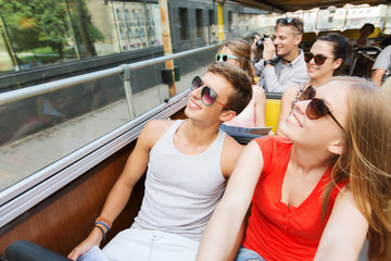 group of smiling friends traveling by tour bus
