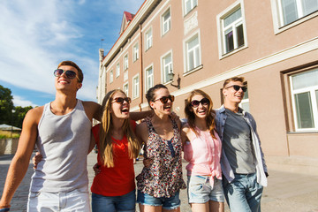 group of smiling friends walking in city