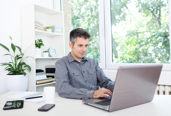Young man at office desk, working on laptop