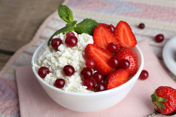 Bowl of cottage cheese with strawberry and cranberry on table, closeup