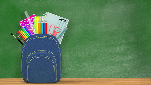 Back to school. A blue Satchel full of school supplies in front of a green blackboard into a classroom. Copy space available.
