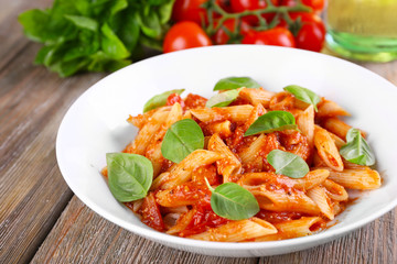 Pasta with tomato sauce and basil on table close up