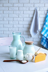 Dairy products on wooden table, on brick wall background