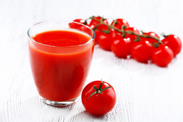 Glass of tomato juice on wooden background