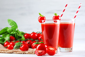 Glasses of tomato juice with vegetables on wooden table background