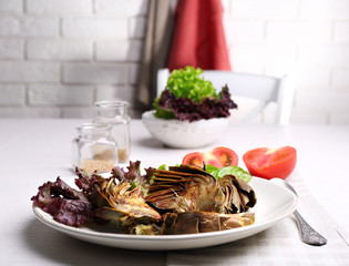 Roasted artichokes on plate, on kitchen table background
