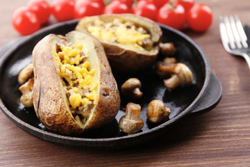 Baked potatoes with cheese and mushrooms on table close up