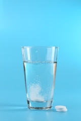 Glass of water and pills on blue background