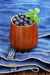 Fresh wild blueberries in wooden vase with wooden spoon on old i